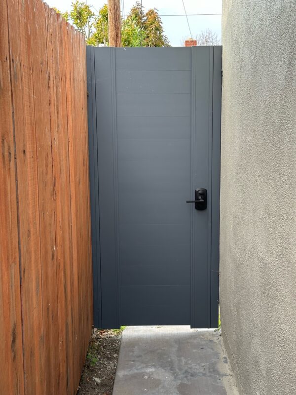 Back view of pedestrian gate against a wooden fence