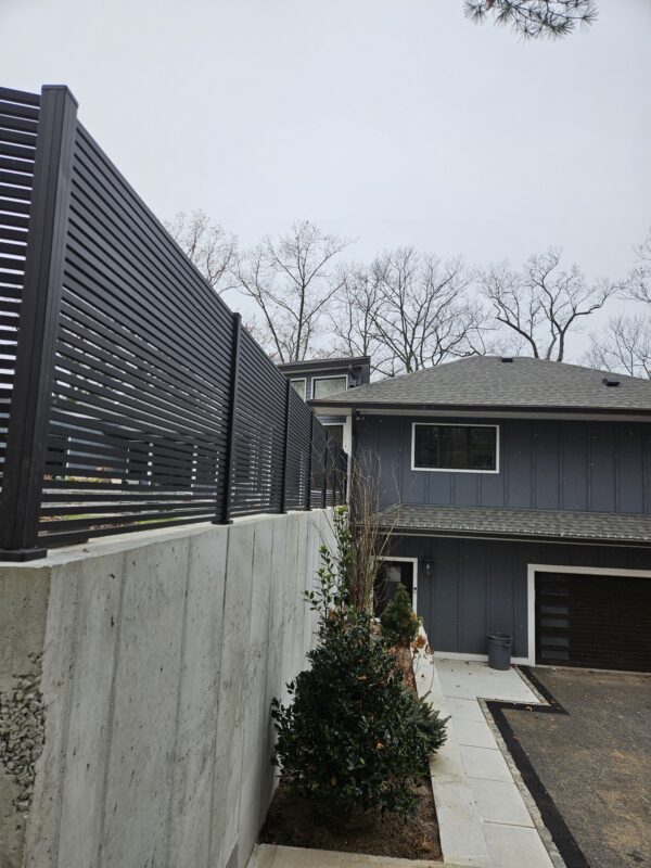 Side view of black aluminum wall topper lining a residential area