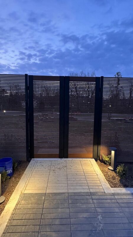 Full View of Wood Finish High Fence and Pedestrian Gate with Lit Pathway and Landscaping