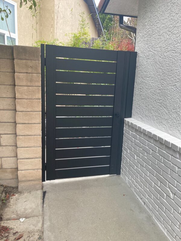 Back View of a Black Pedestrian Gate Installed On Side of a House