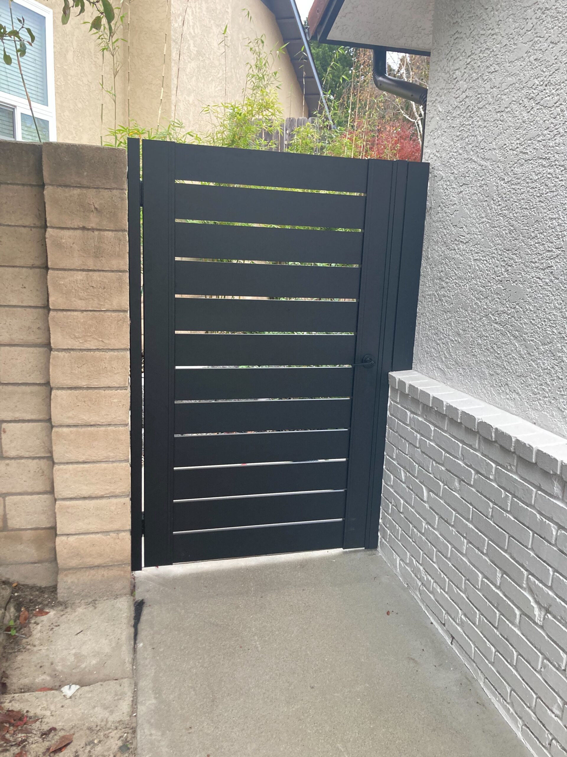 Back View of a Black Pedestrian Gate Installed On Side of a House
