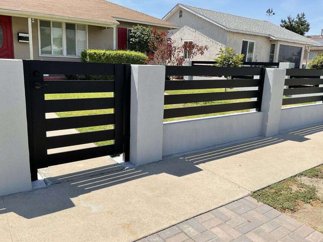 Modern black aluminum fence and gate installed in a residential front yard.