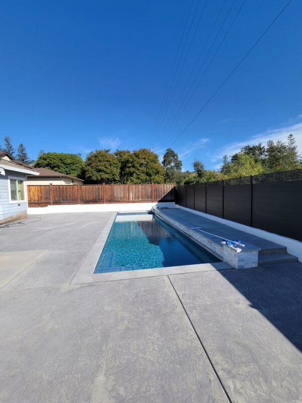 Modern black aluminum fence around a swimming pool in a residential backyard.