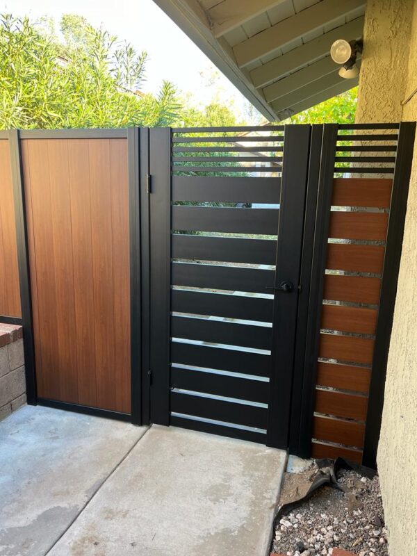 Modern black and wood pedestrian gate installed next to a home, providing style and privacy.