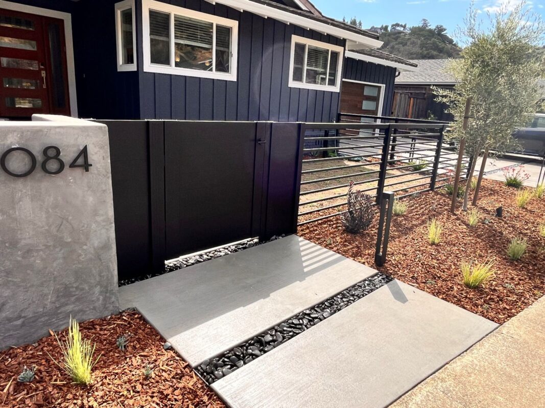 Modern black fence with top rail installed in a landscaped entryway in San Carlos, CA.