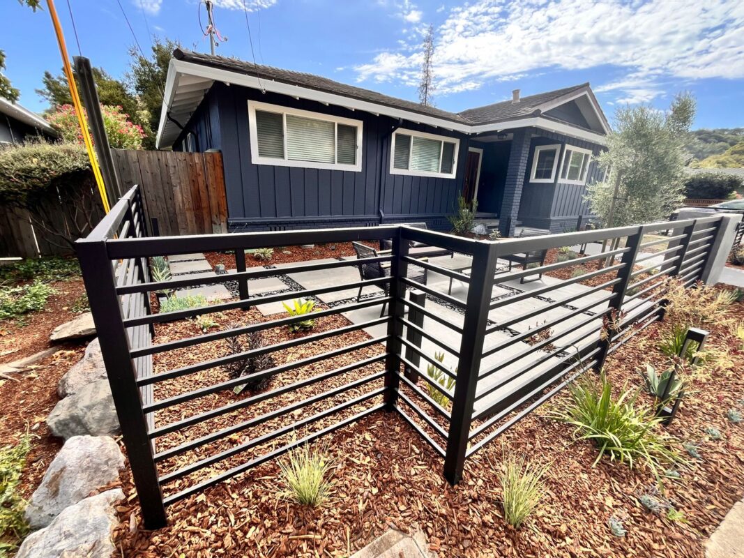 Modern black fence with top rail enhances landscaping in San Carlos, CA.