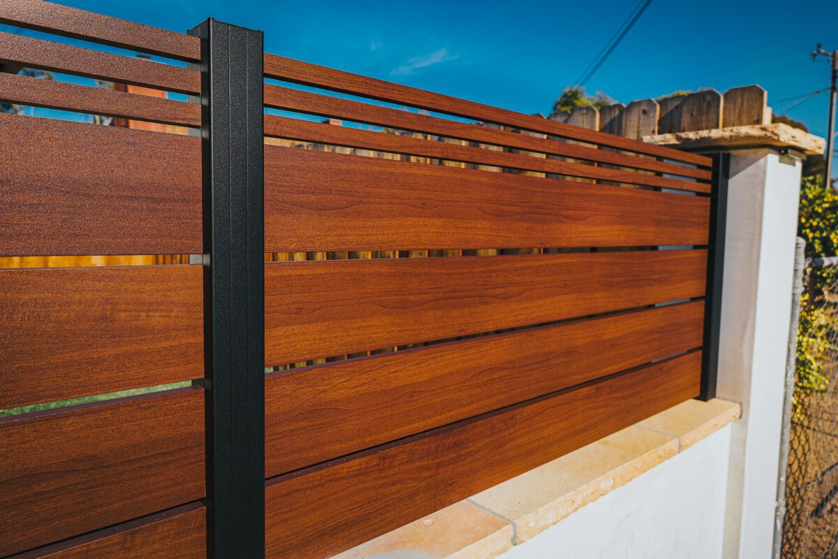Close-up of a modern aluminum fence with a wood-like finish, showcasing durability.