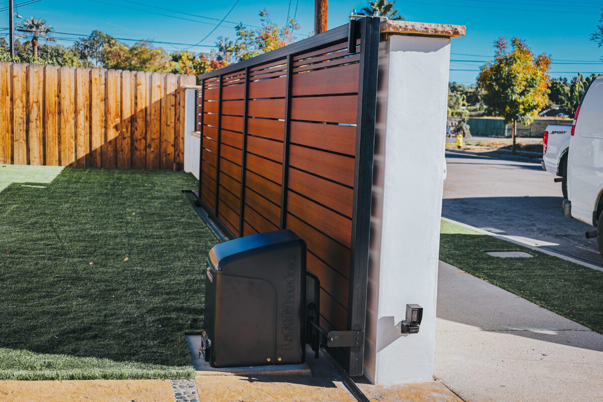 Modern aluminum gate with wood-like finish in a residential yard.