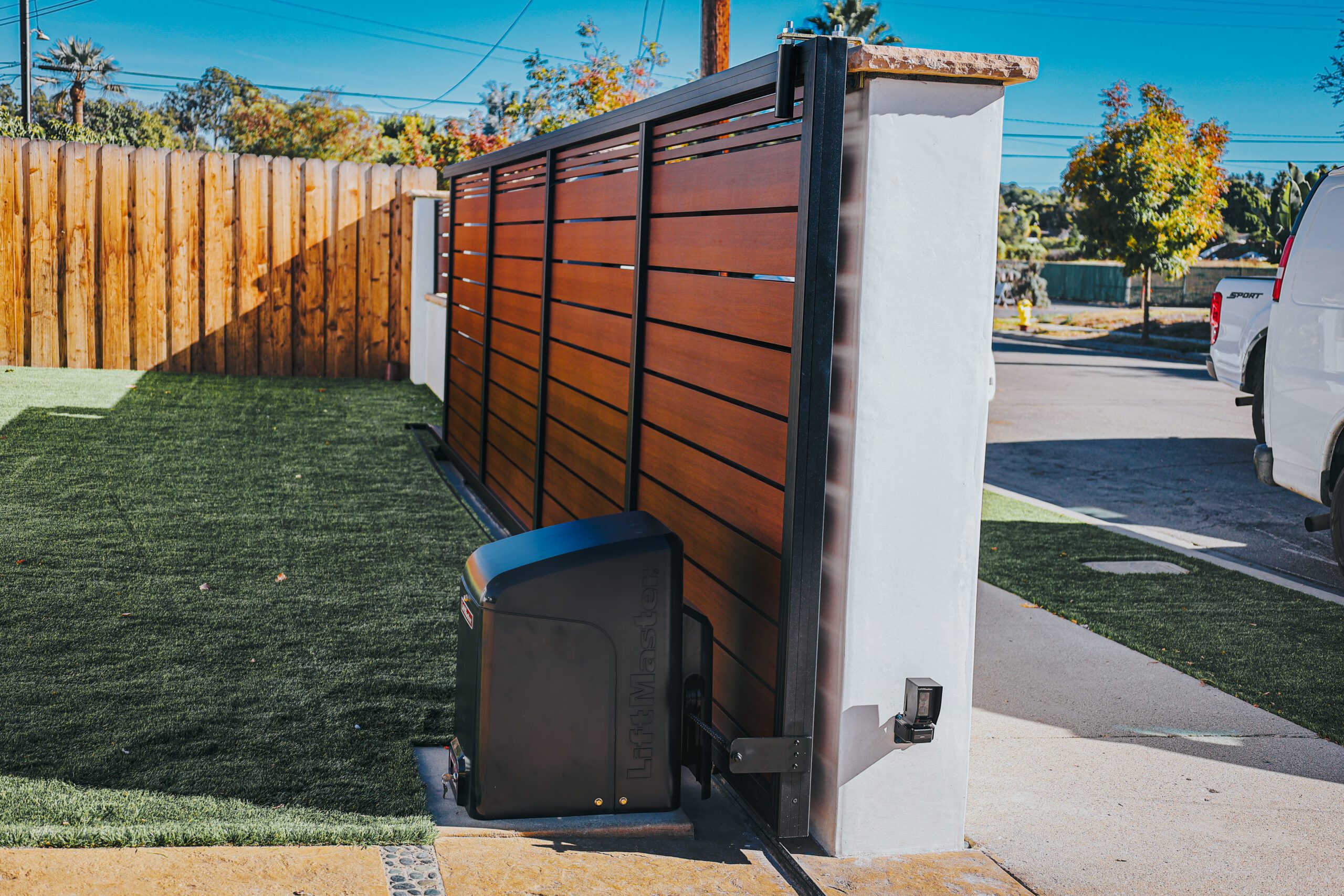 Modern aluminum gate with wood-like finish in a residential yard.