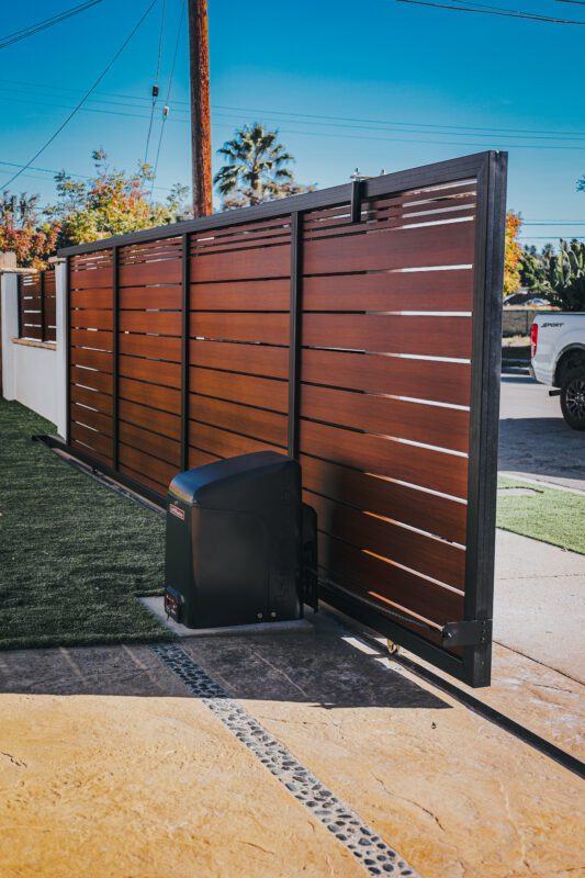 Modern aluminum fence gate installation showcasing wooden appearance and automated function.