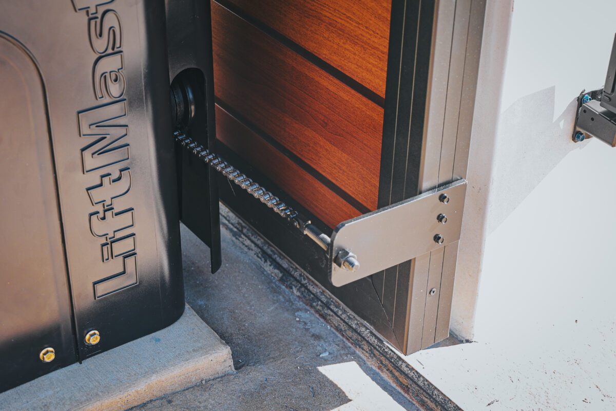 Close-up of a 'Look Like Wood' aluminum gate installation with mechanized components.
