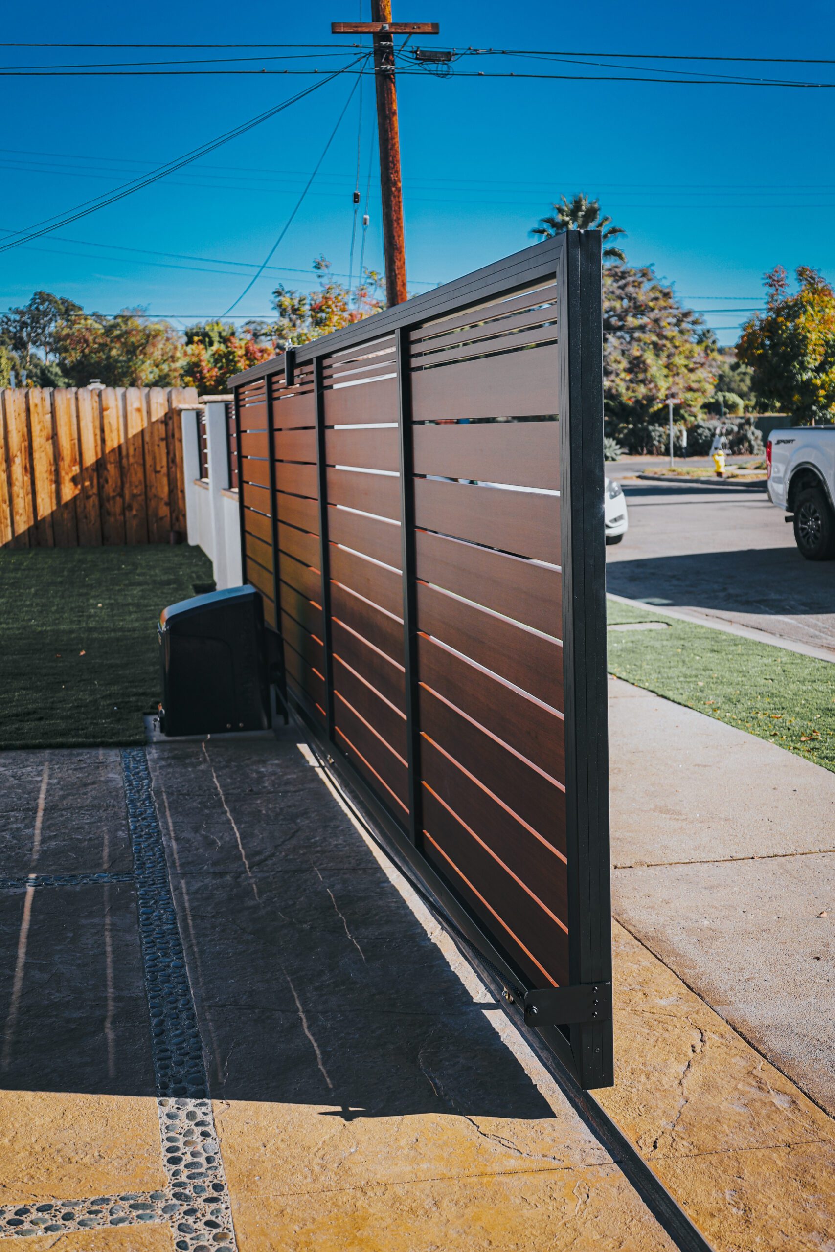 Modern aluminum fence with wood-like finish, installed in a residential area.