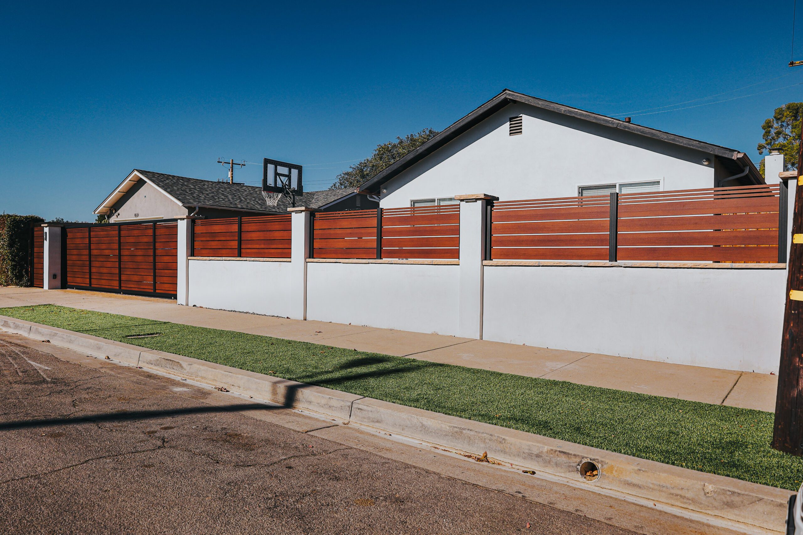 Modern aluminum fence with a wood-like appearance in a residential setting.