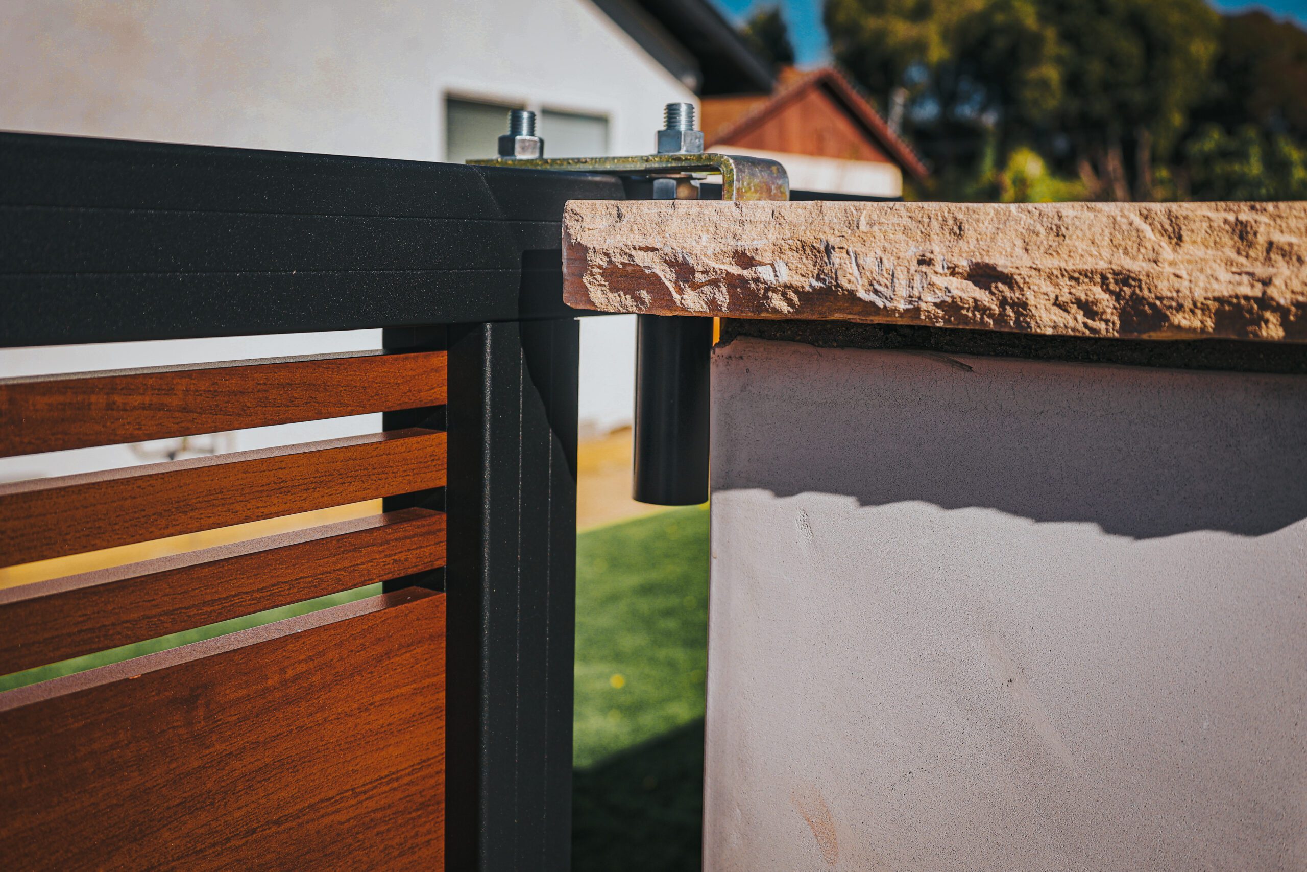 Close-up of a modern aluminum fence with a wood-like finish, showcasing installation details.