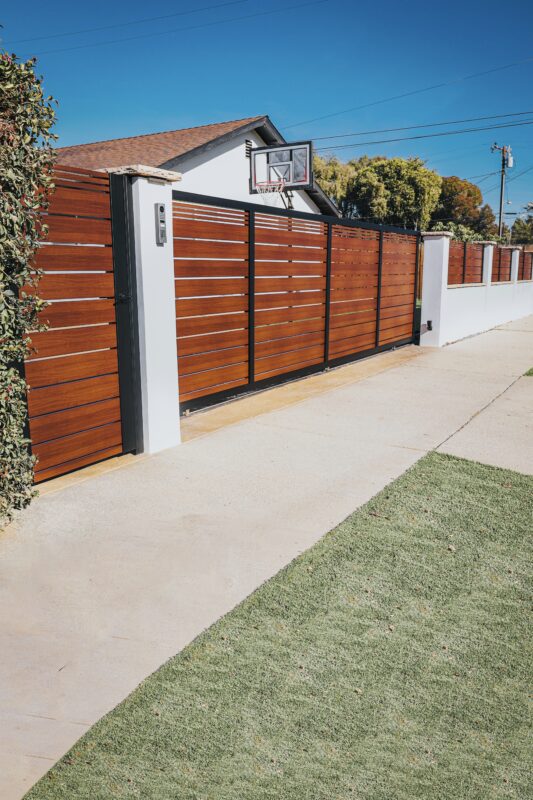 Modern aluminum fence with a wood-like finish installed in a residential area.