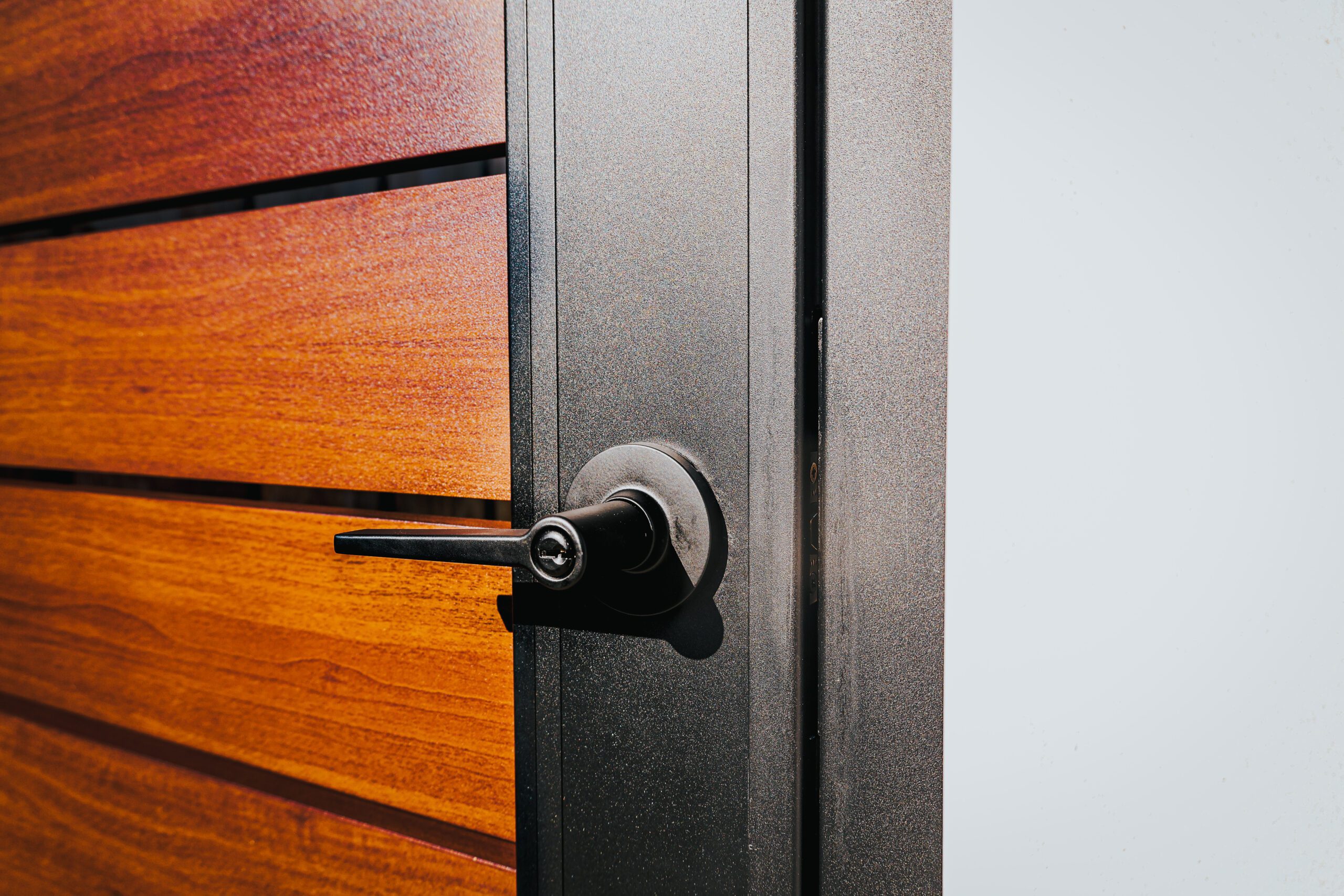 Close-up of a modern aluminum fence gate with a wood-like finish and sleek handle.