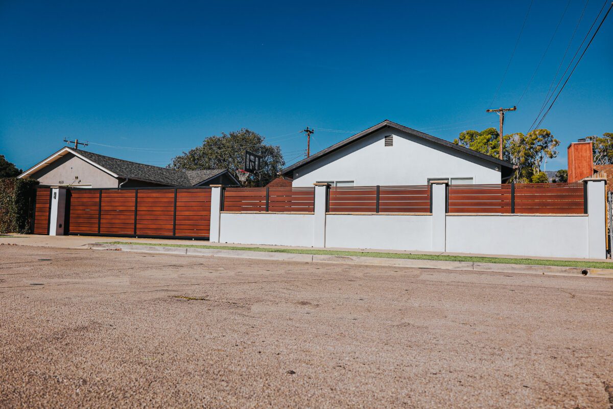 Modern aluminum fence resembling wood, installed around a residential property.