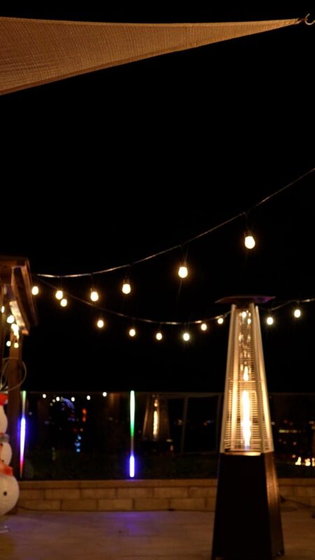 Night view of a patio with string lights, highlighting a modern aluminum fence.