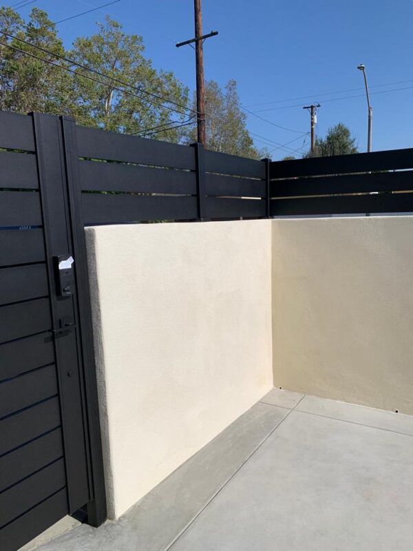 New black aluminum fence and wall topper installation in a modern outdoor space.