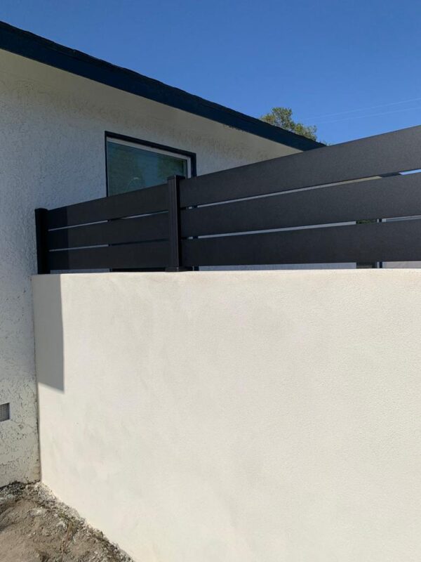 Black aluminum wall topper installed on a white wall, enhancing privacy and style.