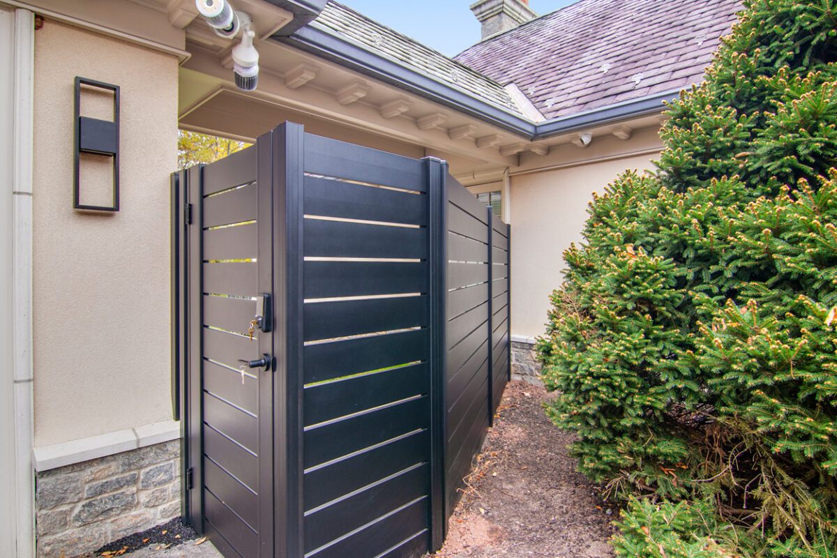 A modern black aluminum fence installation beside a residential property.