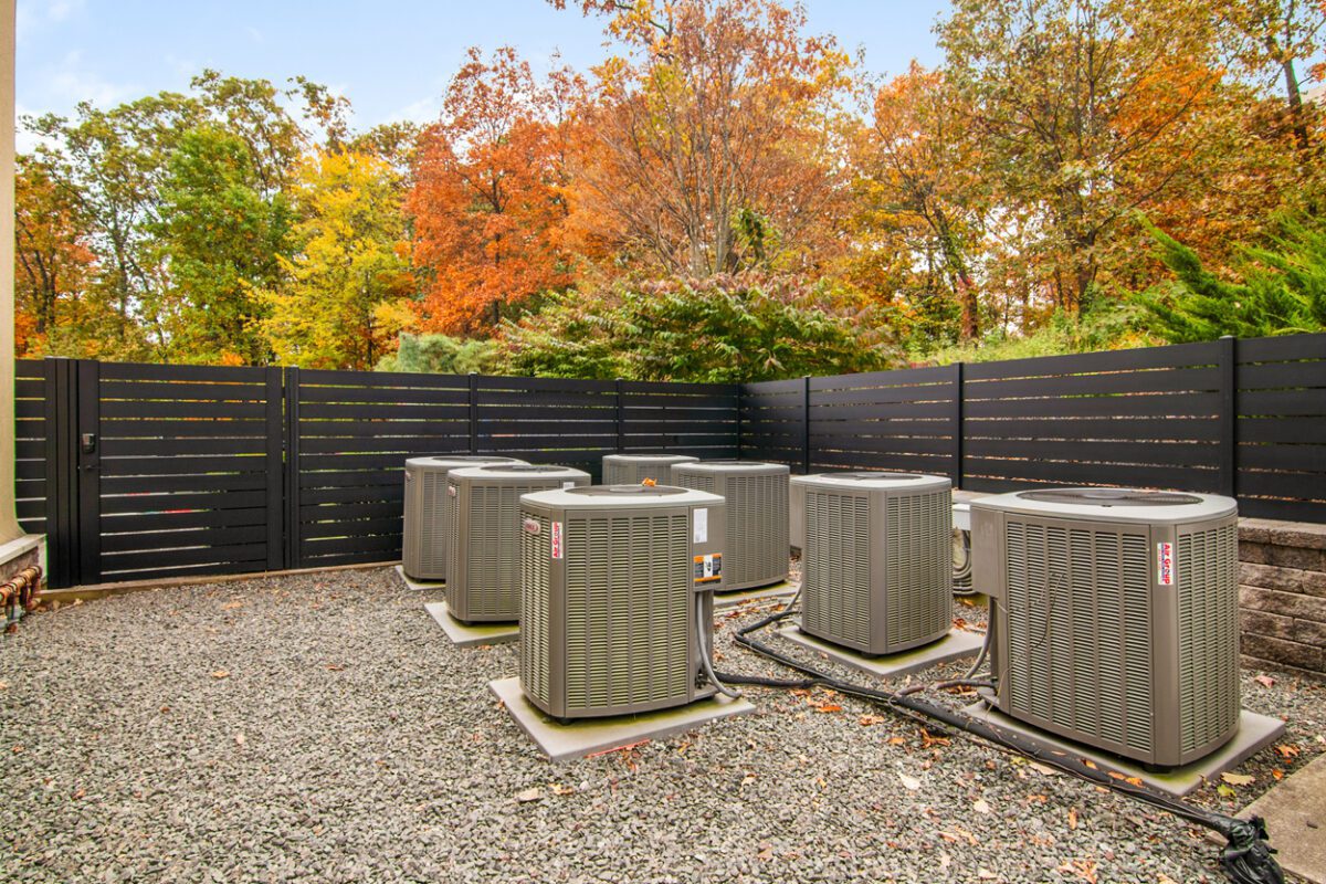 Modern black aluminum fence surrounding HVAC units in a landscaped yard.