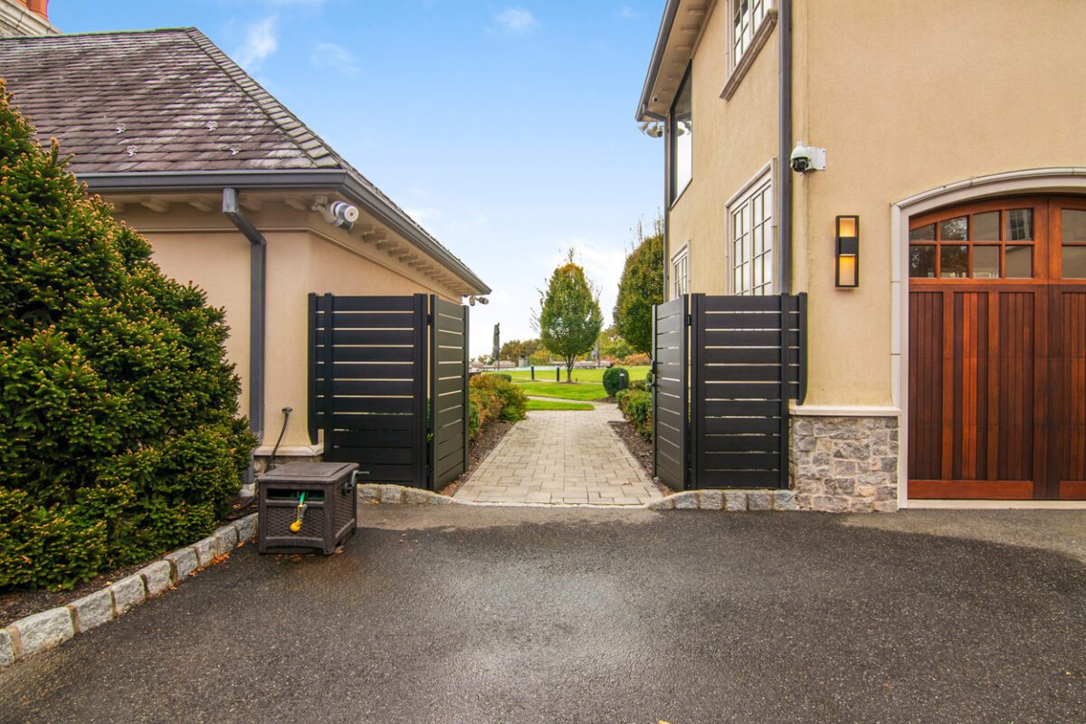 Modern black aluminum fence with double gates, leading to a landscaped yard.
