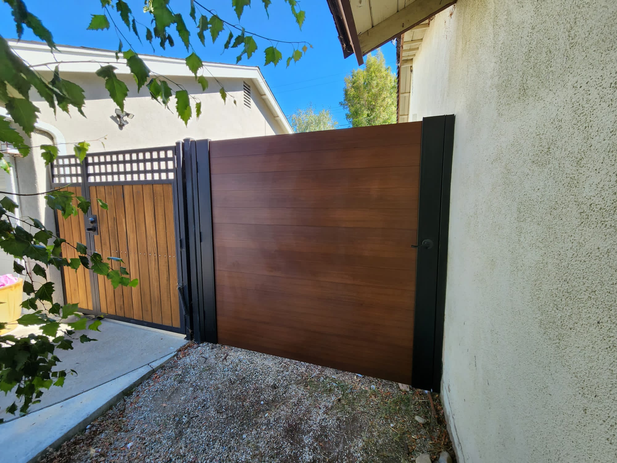 A close-up of a full privacy gate resembling wood, set in a residential area.