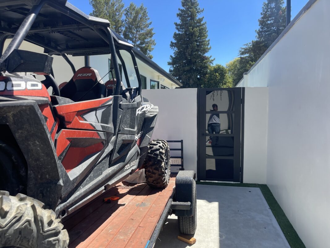 Photo of a black acrylic gate installation next to an off-road vehicle in a modern setting.