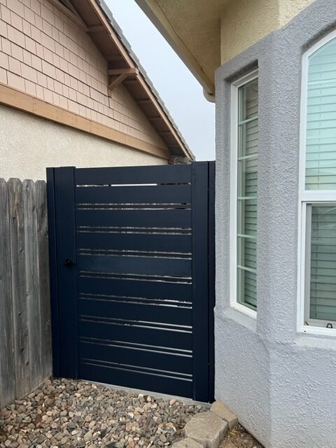 Modern black pedestrian gate installed beside a house, enhancing security and style.