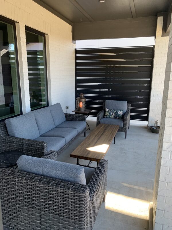 Modern outdoor seating area with black aluminum privacy screen and stylish furniture.