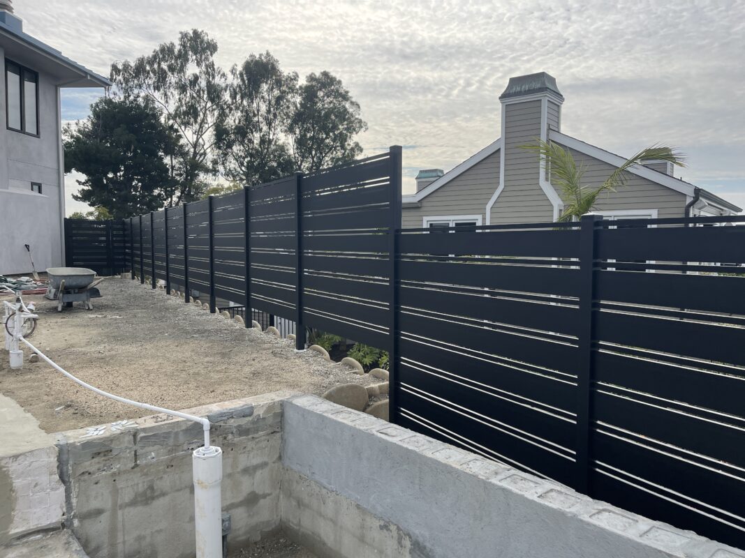 A modern black aluminum fence installed in a Laguna Beach outdoor area.