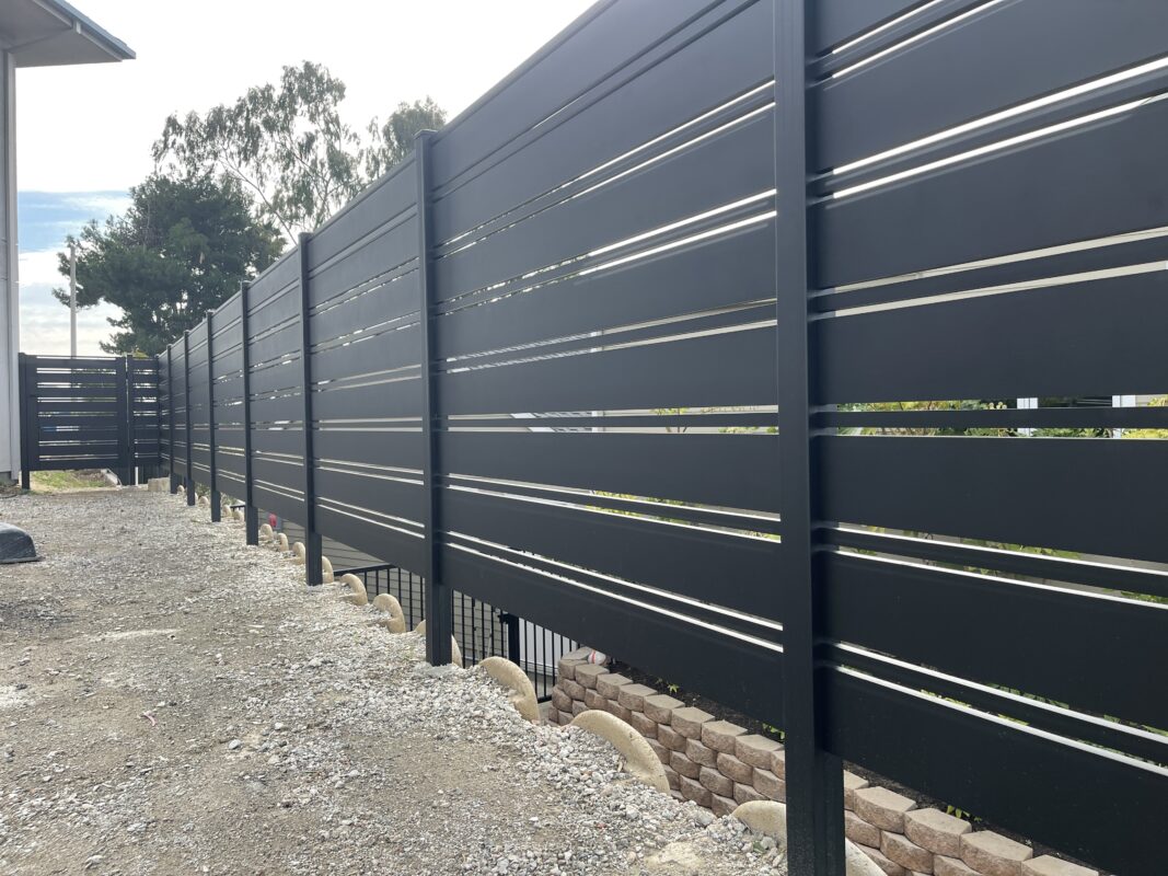 Modern black aluminum fence lines a property, enhancing security and aesthetics.