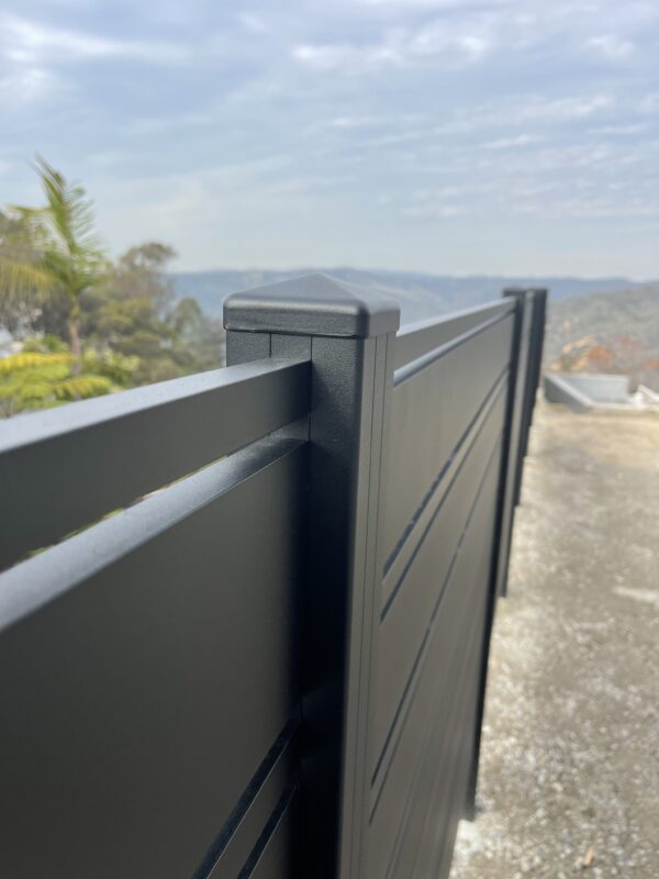 Close-up of a modern black aluminum fence with a scenic view in the background.
