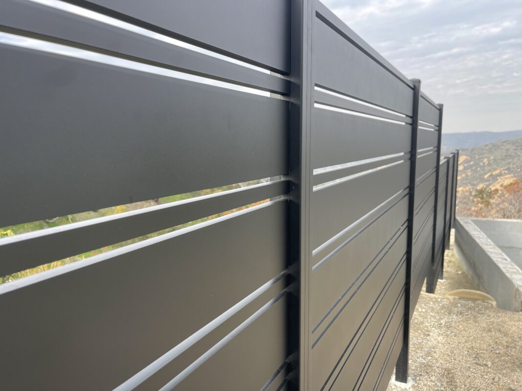 Close-up of a modern black aluminum perimeter fence with horizontal slats.