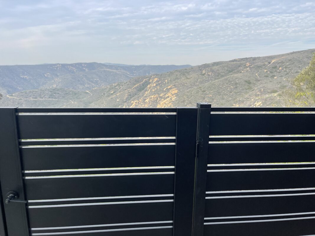 Black aluminum fence overlooking hills, enhancing security and landscape aesthetics.