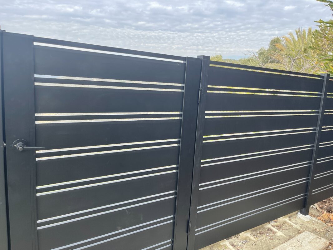 Close-up of a modern black aluminum fence with silver accents in Laguna Beach.