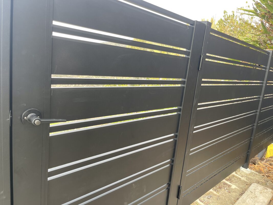 Close-up of a stylish black aluminum perimeter fence with horizontal slats.