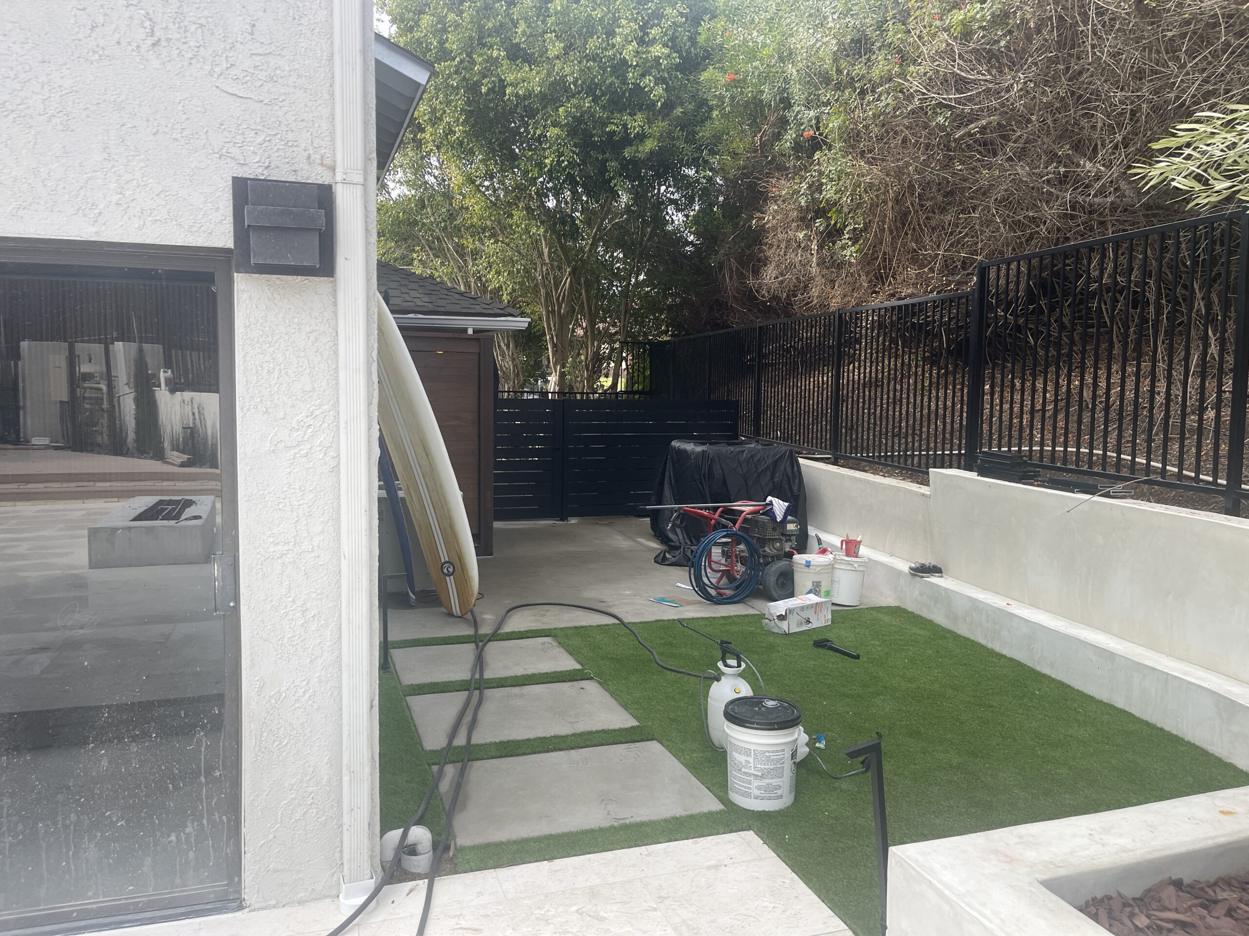Fence installation with black aluminum panels and tools in a landscaped area.