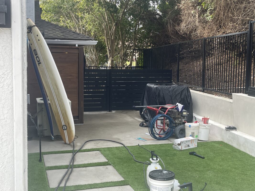 Photo of a fence installation project showing modern black aluminum panels and tools.