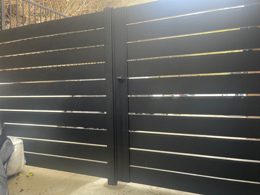 Modern black aluminum fence panels and gate installed for enhanced security and style.