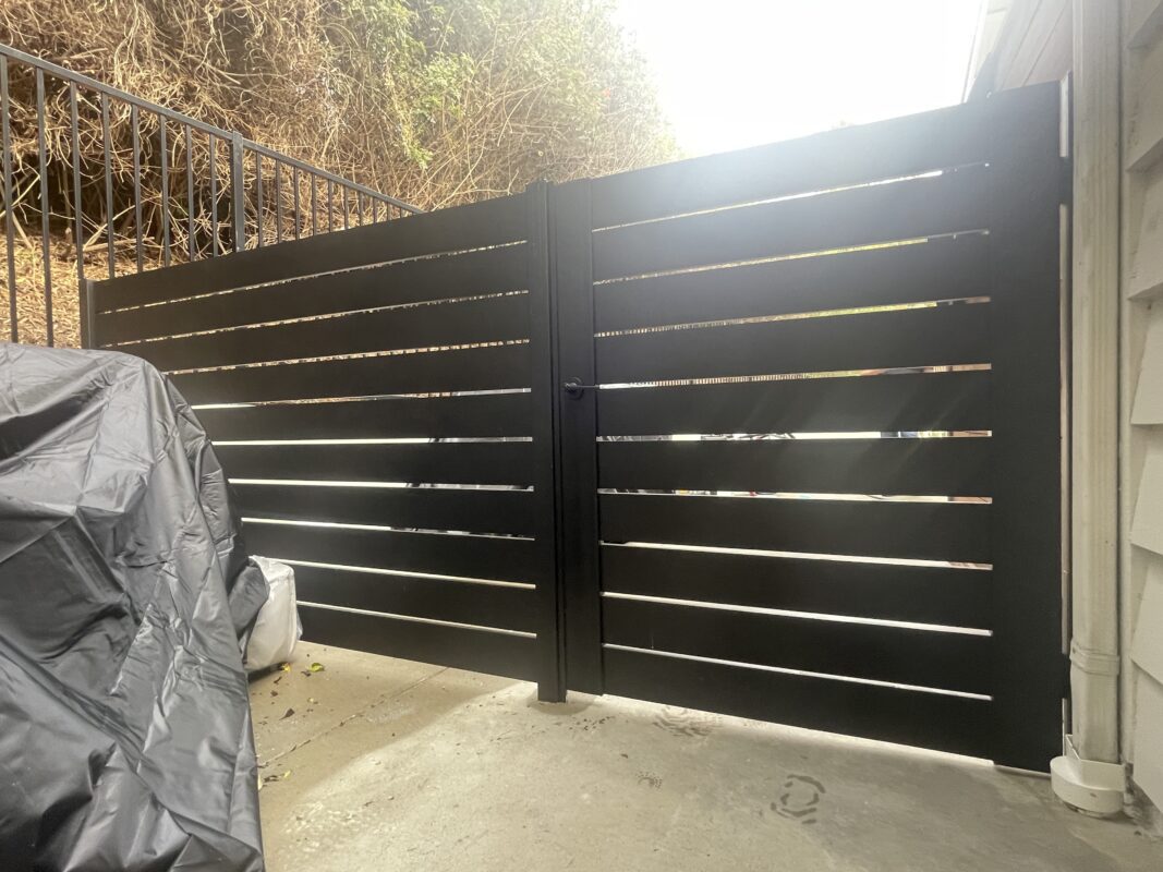 Modern black aluminum gate with horizontal slats, installed at a residential property.