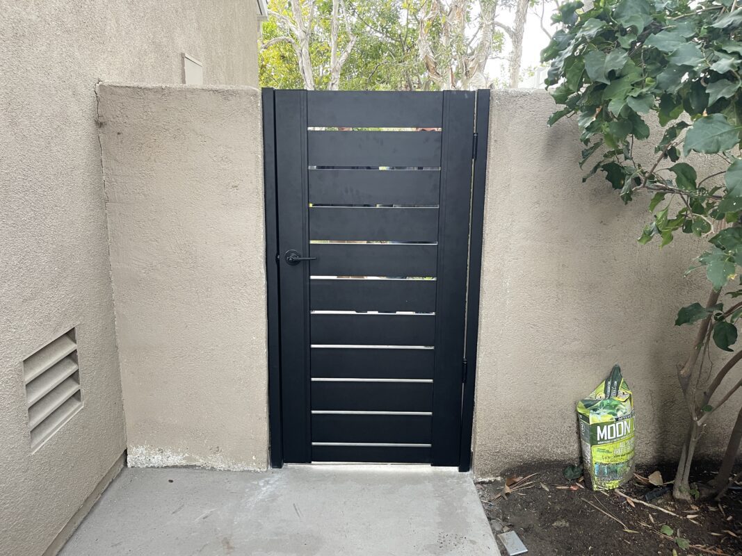 A sleek black powder-coated aluminum gate installed in a modern outdoor space.
