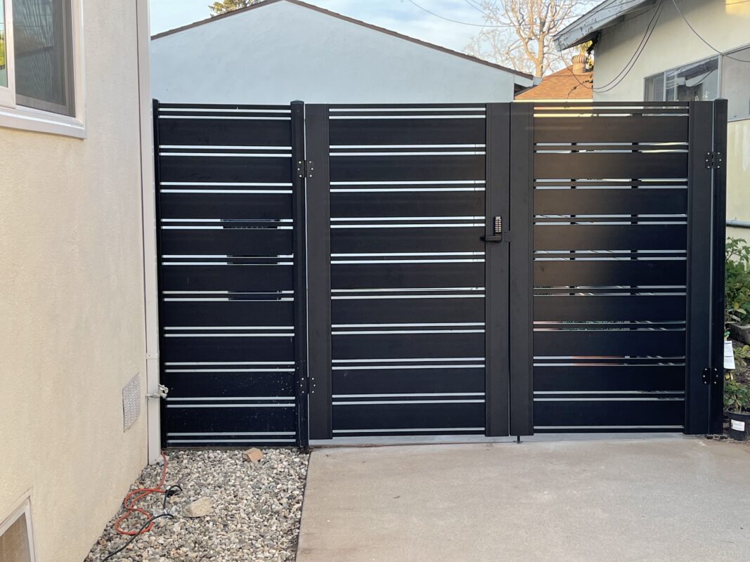 Modern black aluminum double swing gates installed in a residential area.