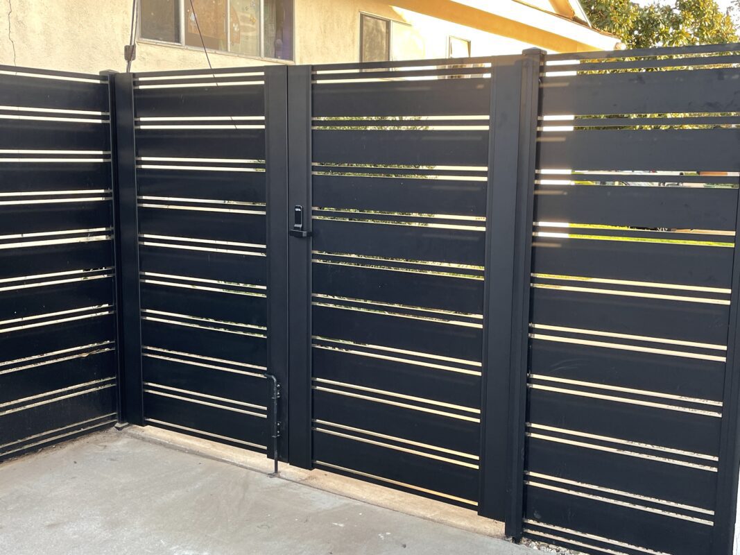 Close-up of a modern black aluminum fence with horizontal slats and a single gate.