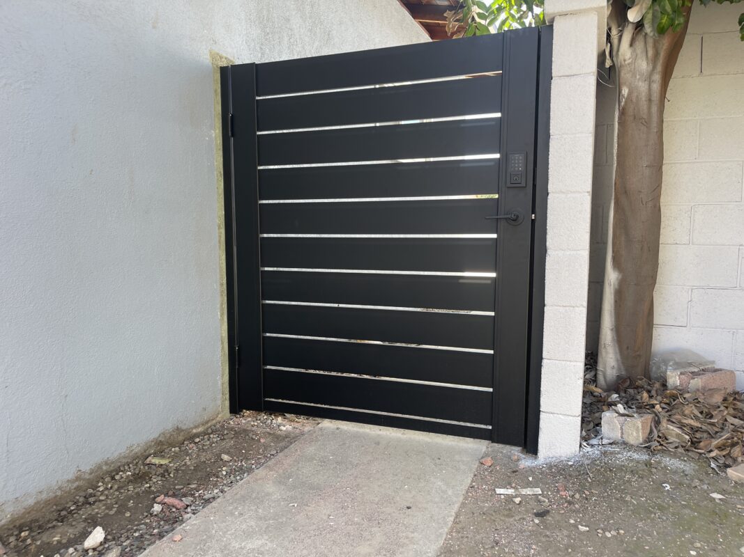 Modern black aluminum gate with sleek horizontal slats installed beside a wall.