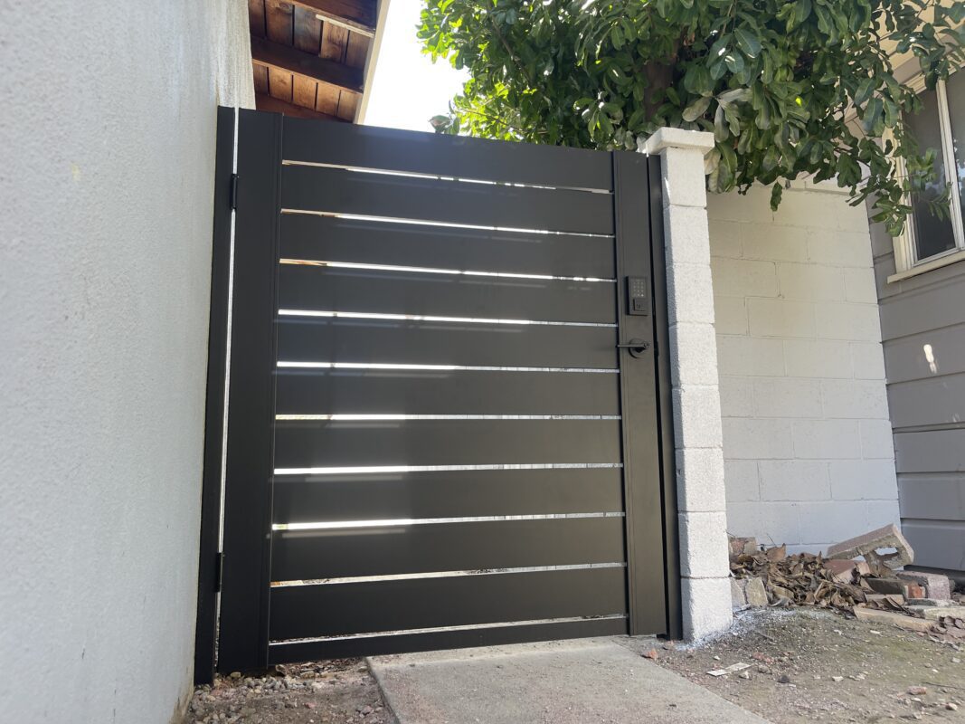 Modern black aluminum gate with horizontal slats. Fence installation in residential area.