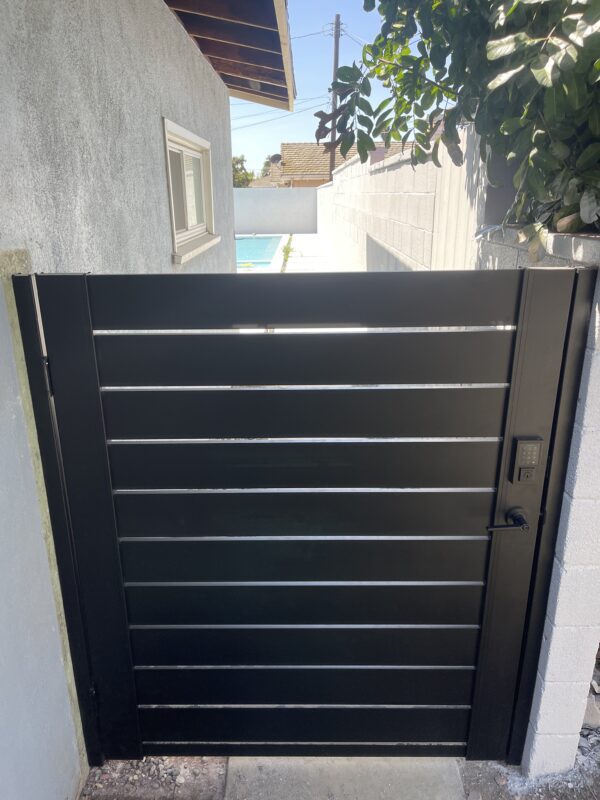 A modern black aluminum gate installed beside a house, enhancing privacy and style.