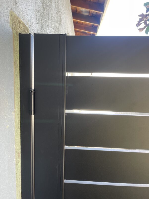 Close-up of a sleek black aluminum side gate installation with modern design features.