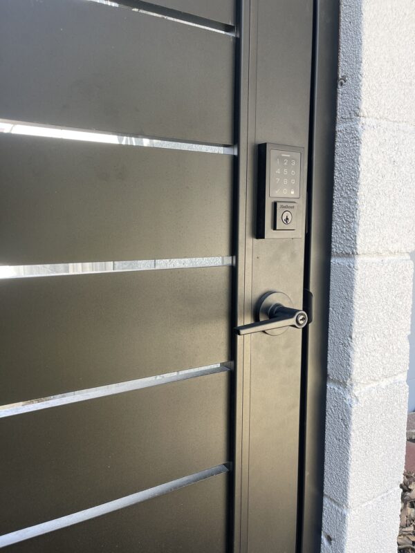 Close-up of a black aluminum gate with keypad lock and sleek design.